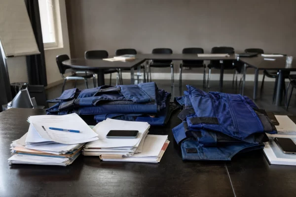 Des gilets de protection posés sur une table de réunion, avec des dossiers et des téléphones autour.