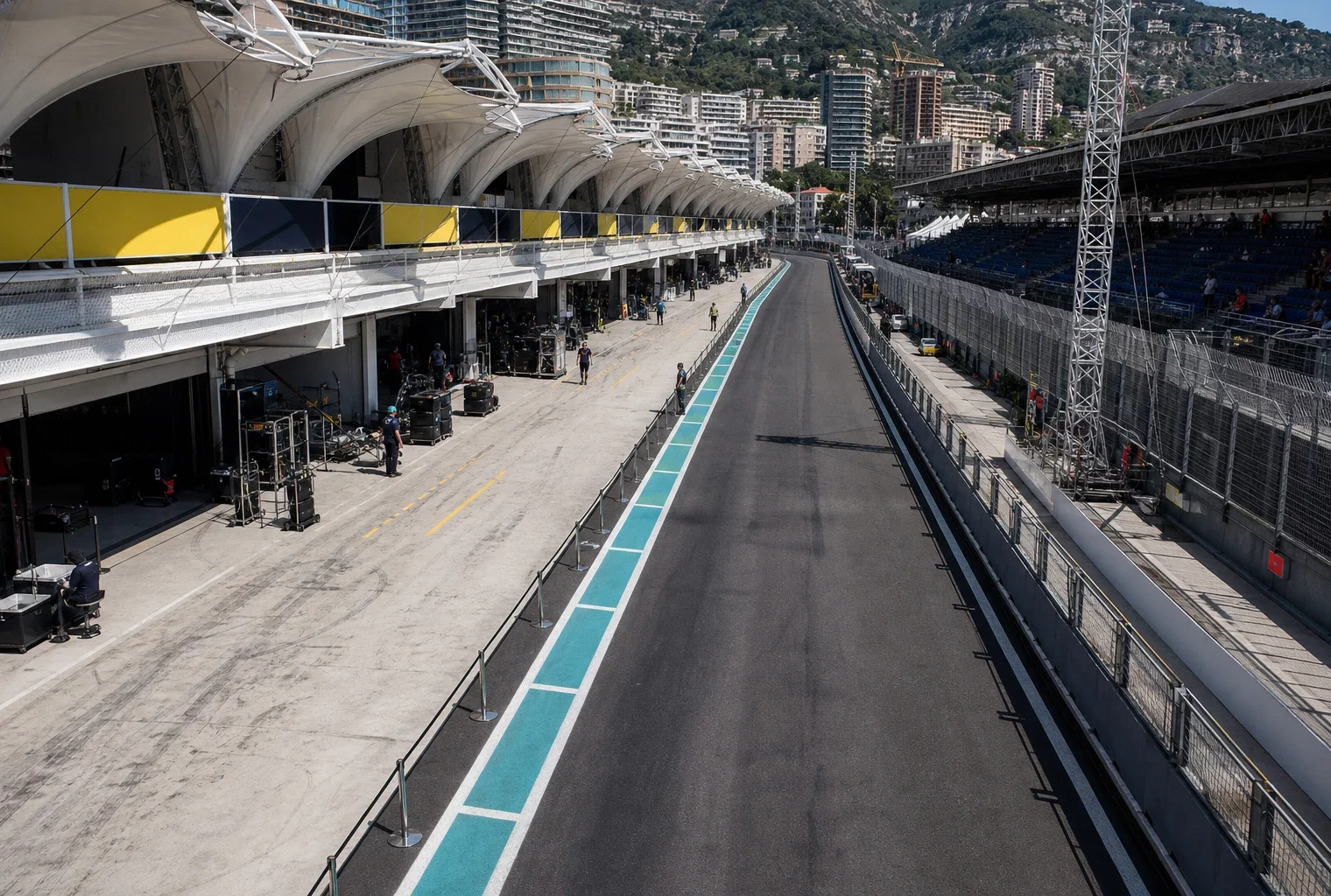 Vue haute du circuit de Monaco, avec rails de sécurité, stands, stands techniques et box sous le soleil de fin de matinée.