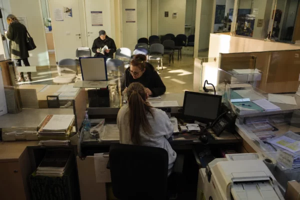 Guichet d’une caisse de retraite avec dossiers et formulaires, image liée au débat sur l’âge de départ.