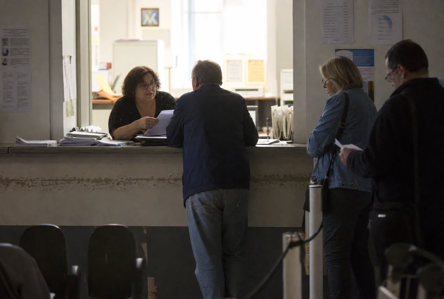Un guichet de service public avec des dossiers, des chaises d’attente et un comptoir administratif.