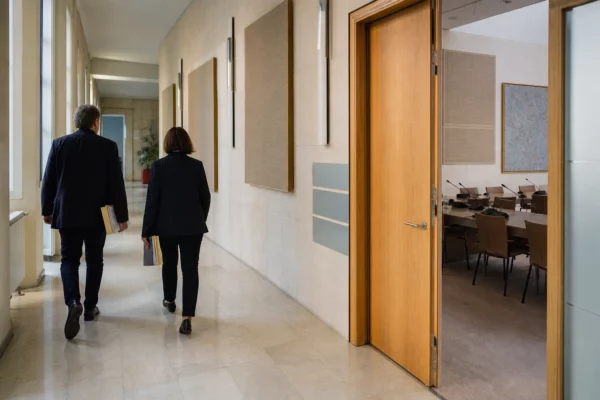 Hall lumineux d’une institution publique française, avec une salle d’audition et des agents anonymes en arrière-plan