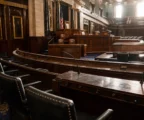 Hémicycle vide de la Chambre des représentants, rangées de pupitres et fauteuils sous boiseries du Capitole.