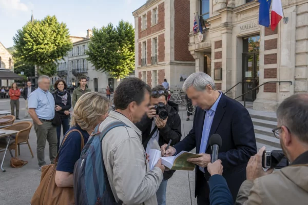 Un responsable politique anonyme échange avec des habitants sur une place de commune française