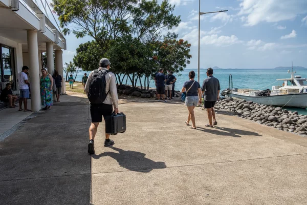 Place côtière de Nouvelle-Calédonie face au Pacifique, avec habitants anonymes et embarcation de pêche au port