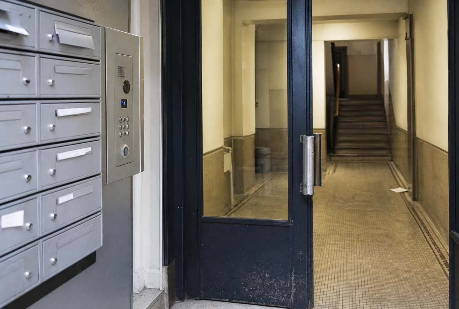 Entrée d’immeuble résidentiel avec boîtes aux lettres et interphone, pour illustrer le poids du loyer sur le budget des retraités.