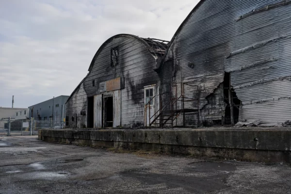 Hangar industriel endommagé par un incendie à Tallinn, façades noircies, portails métalliques et site industriel en arrière-plan.