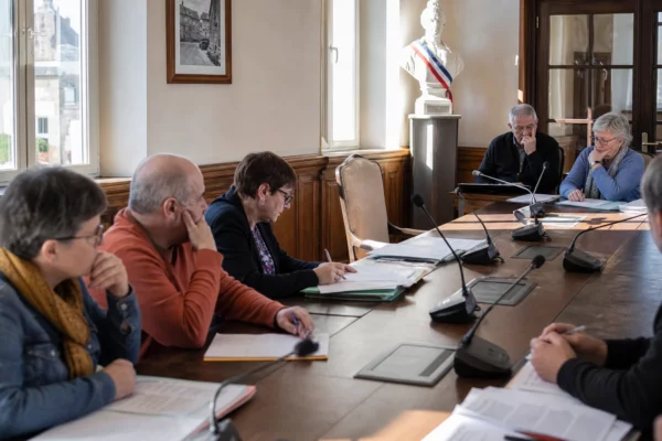 Salle de conseil municipal française avec chaise vide, micros et dossiers flous, illustrant les enjeux de justice
