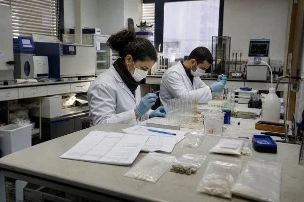 Dans un laboratoire de police scientifique, des échantillons sont analysés sur une paillasse avec tubes et matériel technique.