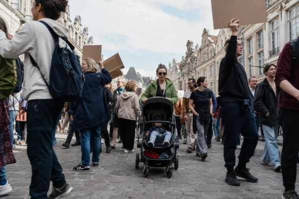 Landau au centre d’une marche pour le climat à Arras, poussé parmi des manifestants et des pancartes, façades de rue en fond.