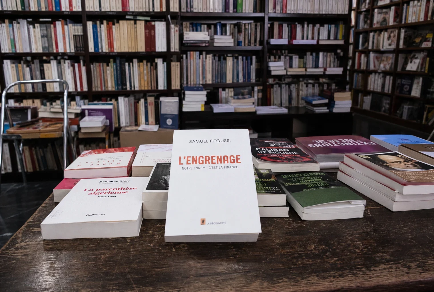 Un livre d’essais politiques posé en librairie, avec d’autres ouvrages autour et des rayonnages en fond.