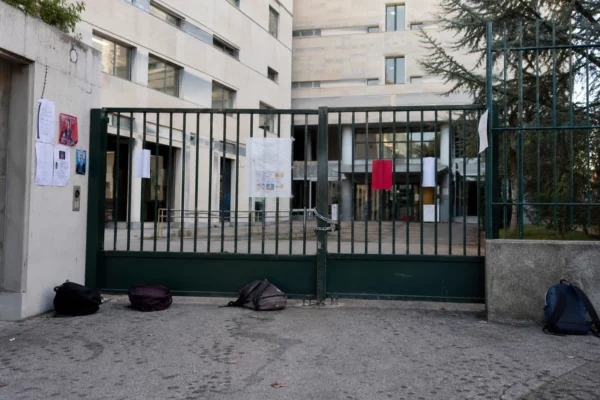 Entrée d’un lycée bloquée par des barrières, avec la façade de l’établissement en arrière-plan.