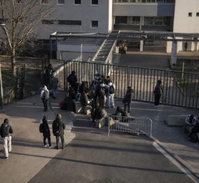 Des grilles de lycée bloquées par des élèves devant l’entrée, avec des barrières de fortune.