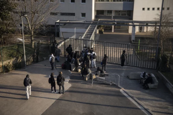 Des grilles de lycée bloquées par des élèves devant l’entrée, avec des barrières de fortune.
