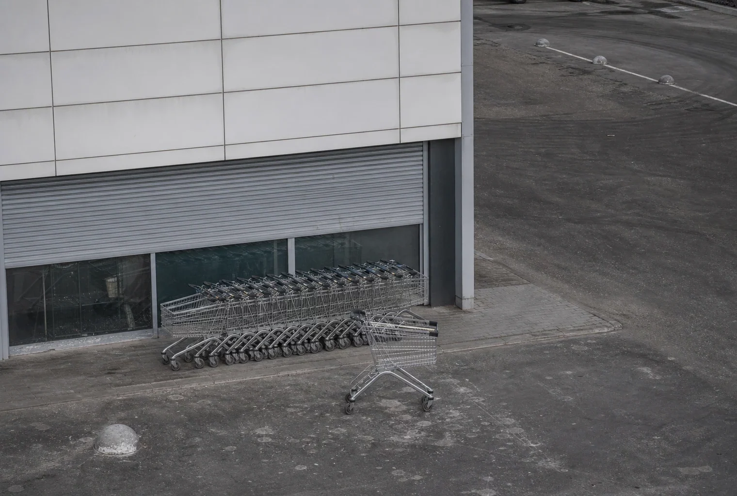 Devanture de magasin en Russie avec chariots alignés, rideau de sécurité abaissé et parking vide sous lumière diffuse.