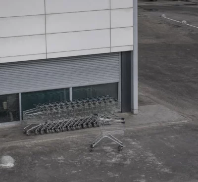 Devanture de magasin en Russie avec chariots alignés, rideau de sécurité abaissé et parking vide sous lumière diffuse.