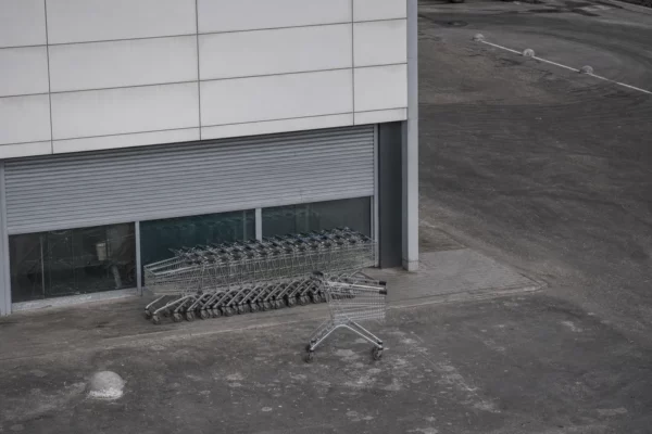 Devanture de magasin en Russie avec chariots alignés, rideau de sécurité abaissé et parking vide sous lumière diffuse.