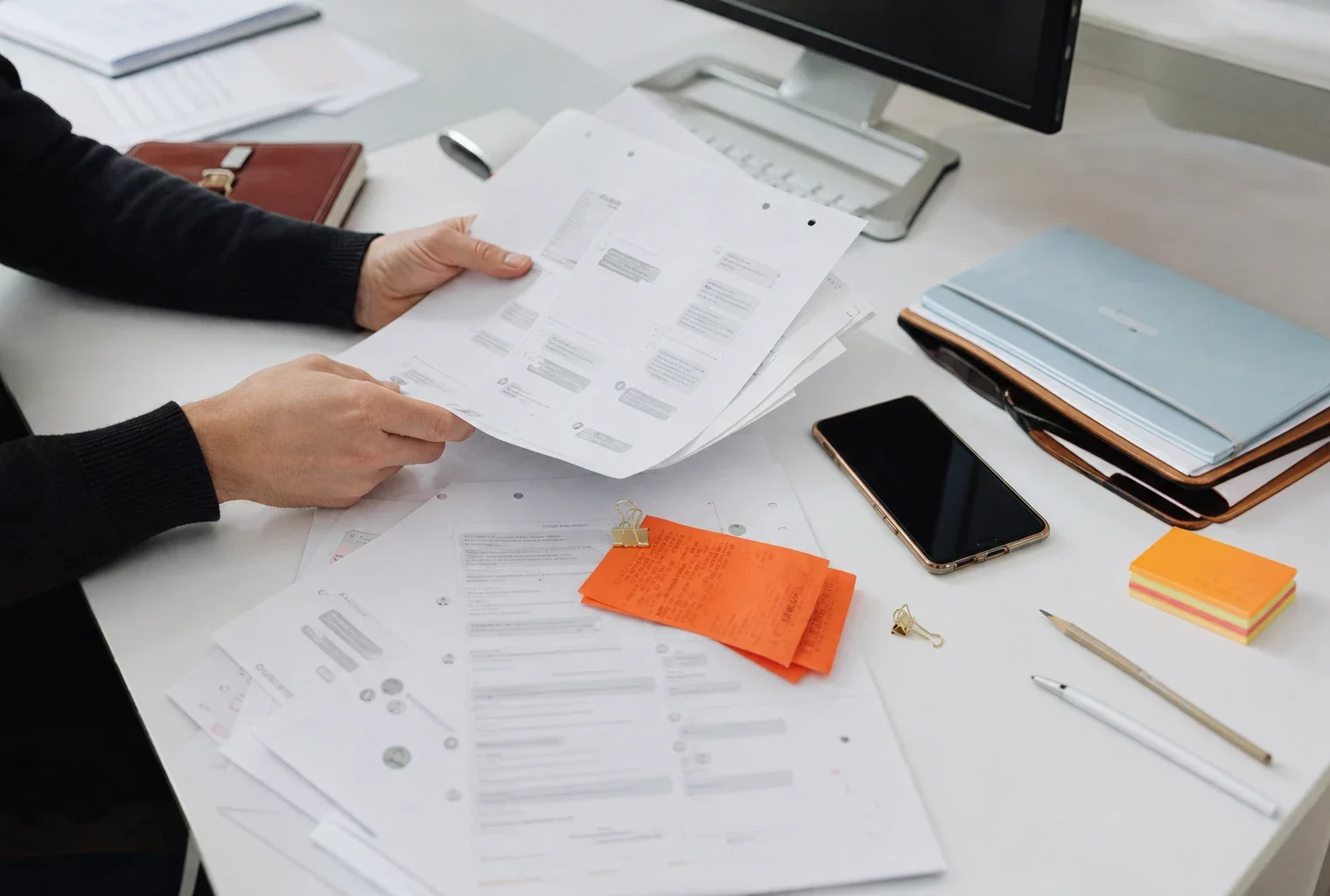 Vue en plongée d’un bureau d’avocat avec feuilles imprimées, téléphone et mains consultant d’anciens échanges.