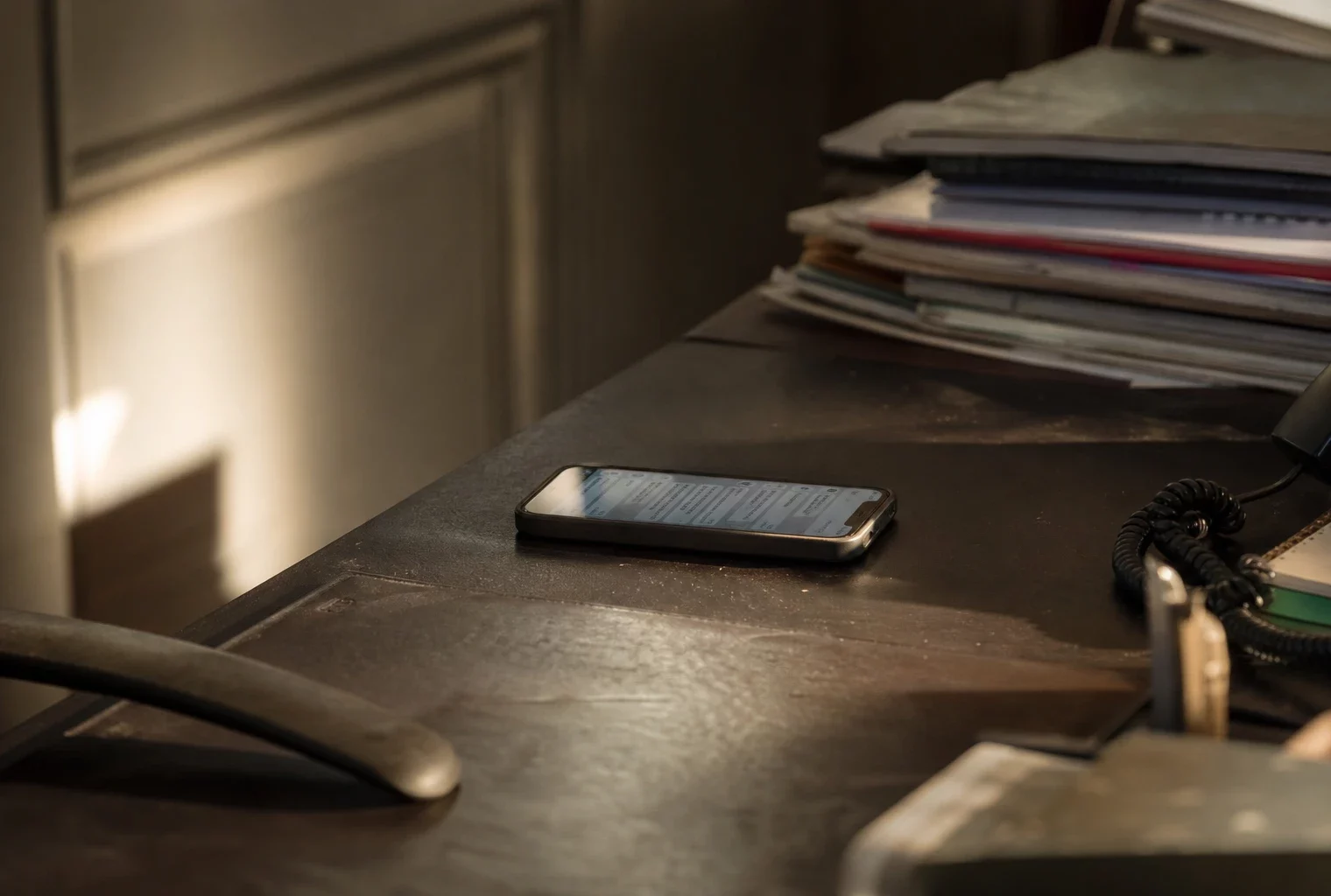Un smartphone posé sur une table montre une conversation privée, dans un cadre sobre de bureau.