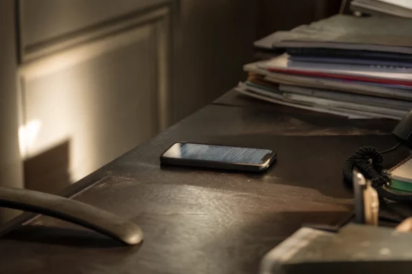 Un smartphone posé sur une table montre une conversation privée, dans un cadre sobre de bureau.