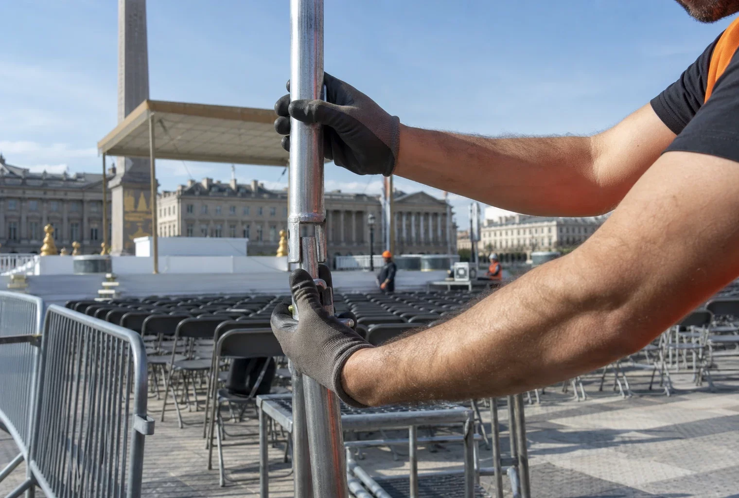 Installation d’une messe en plein air sur une grande place parisienne, avec chaises alignées et barrières de sécurité.