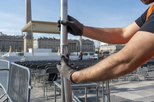 Installation d’une messe en plein air sur une grande place parisienne, avec chaises alignées et barrières de sécurité.