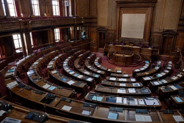 Salle du conseil municipal de Nice vue en plongée, pupitres alignés, micros et dossiers, ambiance institutionnelle vide.