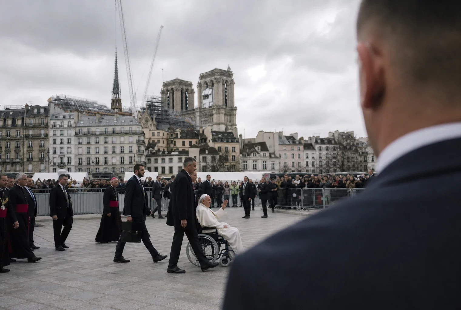 Notre-Dame vue depuis le parvis, avec barrières de sécurité au premier plan et façade de la cathédrale en arrière-plan sous ciel gris.