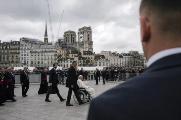 Notre-Dame vue depuis le parvis, avec barrières de sécurité au premier plan et façade de la cathédrale en arrière-plan sous ciel gris.