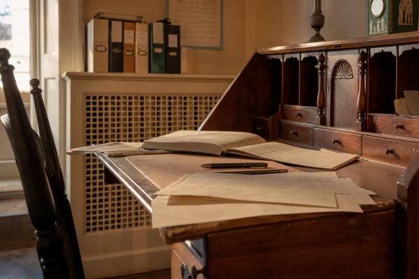 Bureau électoral d’une mairie, avec formulaires de parrainage, registre ouvert, stylos et rangements en bois usés.