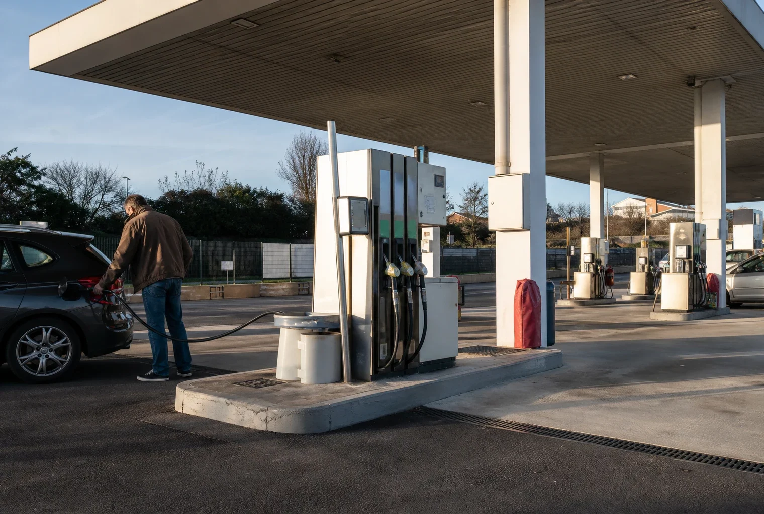 Une pompe à carburant dans une station-service, avec plusieurs pistes de ravitaillement en arrière-plan.
