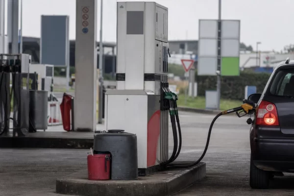 Pompe à carburant dans une station-service, avec une voiture à proximité, pour illustrer le poids des prix de l’énergie.
