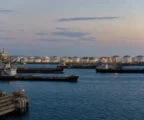 Port pétrolier de Yanbu au crépuscule, avec tankers, cuves de stockage et installations industrielles au bord de l’eau.