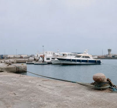 Quai du port de La Seyne-sur-Mer avec bollards, amarres et bateaux de plaisance sous un ciel couvert.