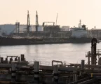 Port pétrolier de Yanbu avec tanker, pipelines et grues de chargement sous une lumière de contre-jour dure.