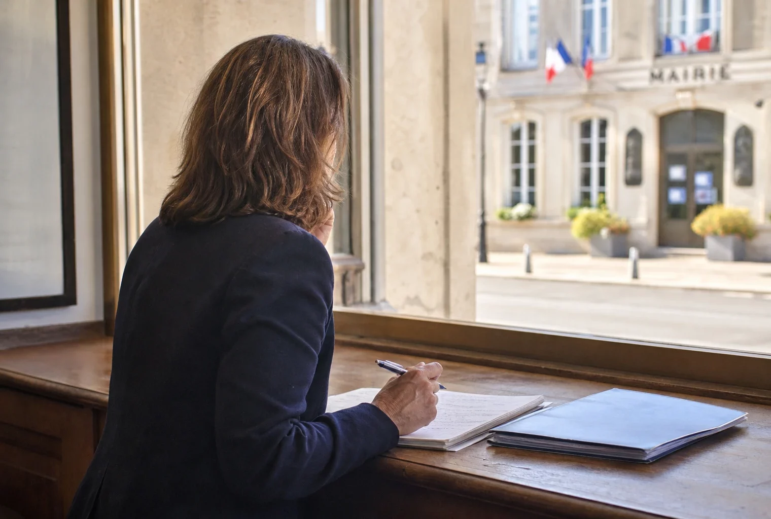 Élu local anonyme prenant des notes sur le budget dans une mairie française lumineuse