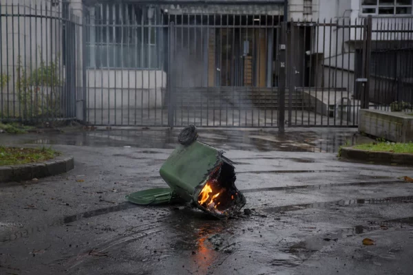 Une poubelle en feu est déplacée devant les grilles d’un lycée, au milieu d’un blocage lycéen.