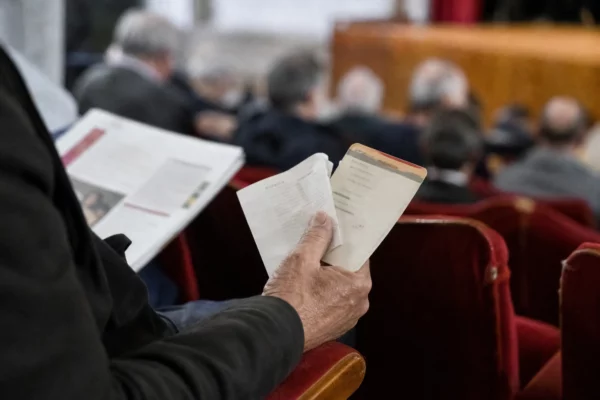 Main tenant un ticket et un reçu de carburant sur le fauteuil usé d’une salle culturelle française