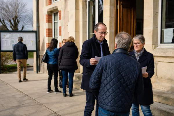 Citoyens anonymes échangeant devant une mairie française lors d’une réunion publique locale