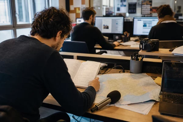 Journaliste préparant un sujet sur une primaire politique dans une rédaction locale française, avec micro et carte floue