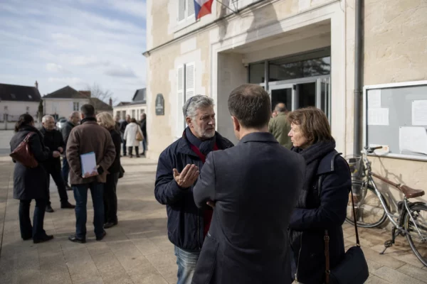 Citoyens anonymes échangeant devant une mairie française lors d’une réunion politique locale
