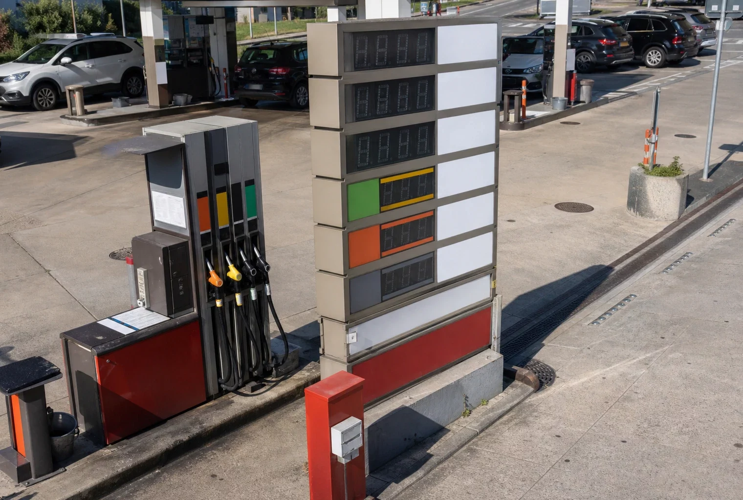 Panneau des prix d’une station-service en France, avec les pompes et des voitures en arrière-plan.