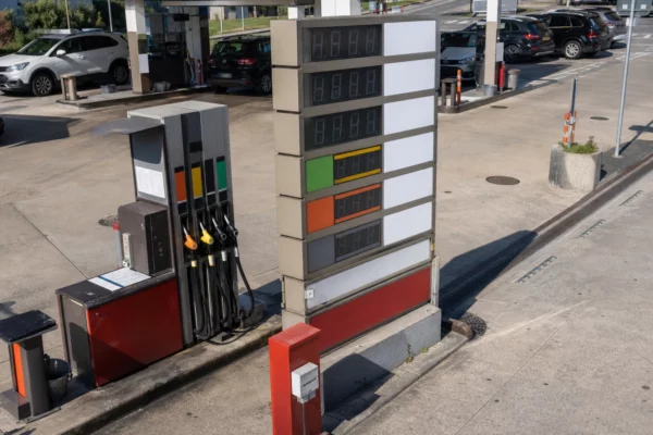 Panneau des prix d’une station-service en France, avec les pompes et des voitures en arrière-plan.