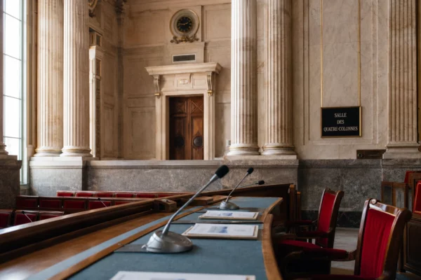 Salle parlementaire française éclairée par la lumière naturelle, avec micros et dossiers liés à la protection des scrutins