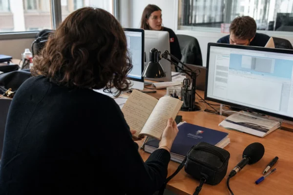 Rédaction française préparant un sujet sur le contrôle des soignants, avec carnet, micro et écrans abstraits