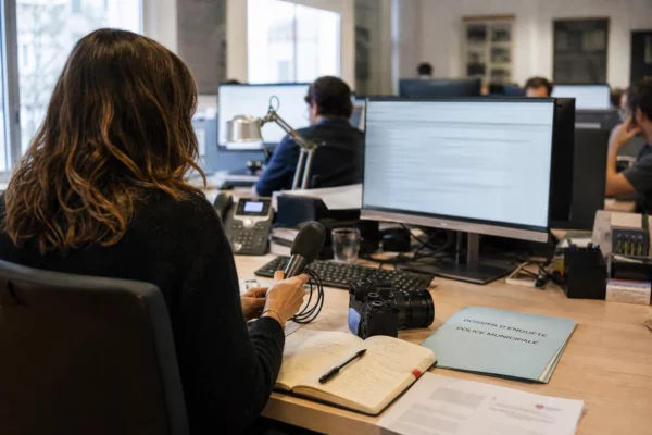 Rédaction française préparant une enquête sur la police municipale, avec micro, carnet et écrans abstraits