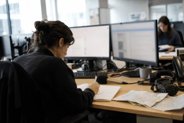 Journaliste préparant un sujet politique dans une rédaction locale française, avec carnet, micro et carte floue