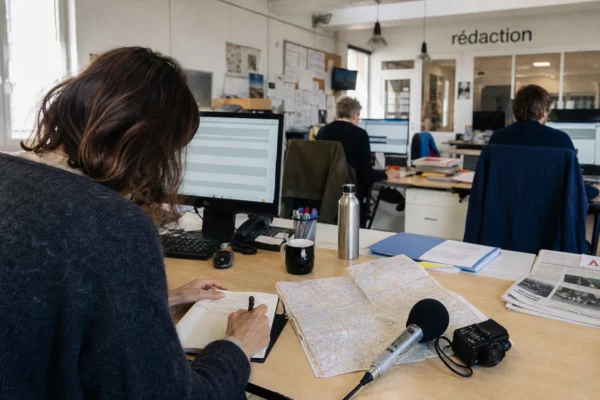 Journaliste préparant dans une rédaction locale un sujet sur la hausse des carburants et son impact territorial