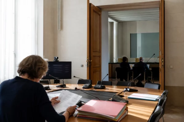 Salle claire d’un régulateur audiovisuel français avec micros, dossiers et écran de visioconférence éteint