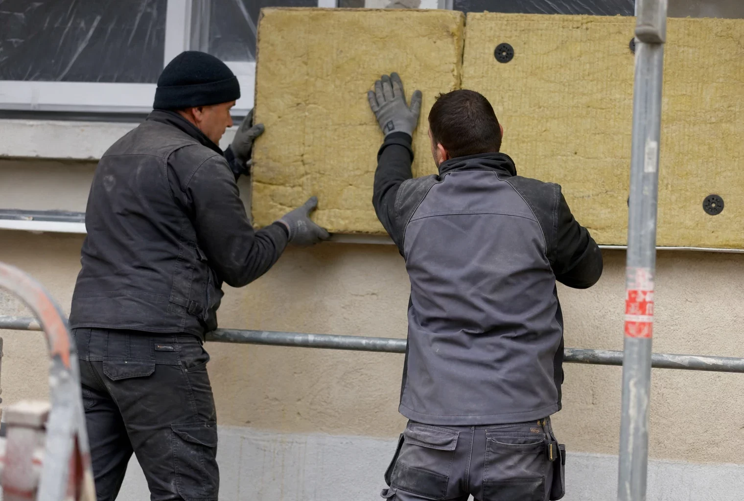 Chantier de rénovation thermique d’un immeuble, avec échafaudages et matériaux d’isolation en façade.