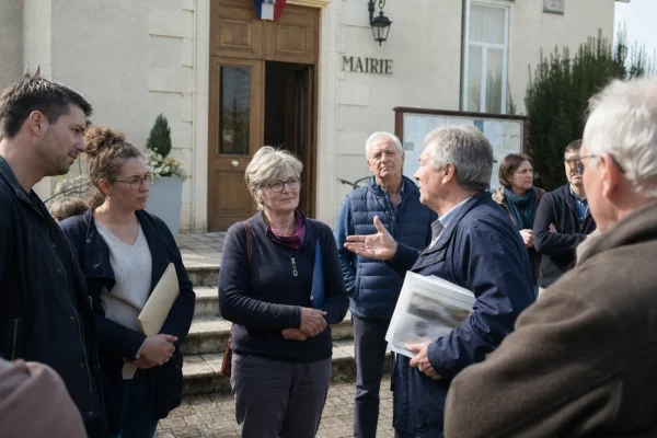 Citoyens anonymes réunis devant une mairie française pour une discussion politique locale